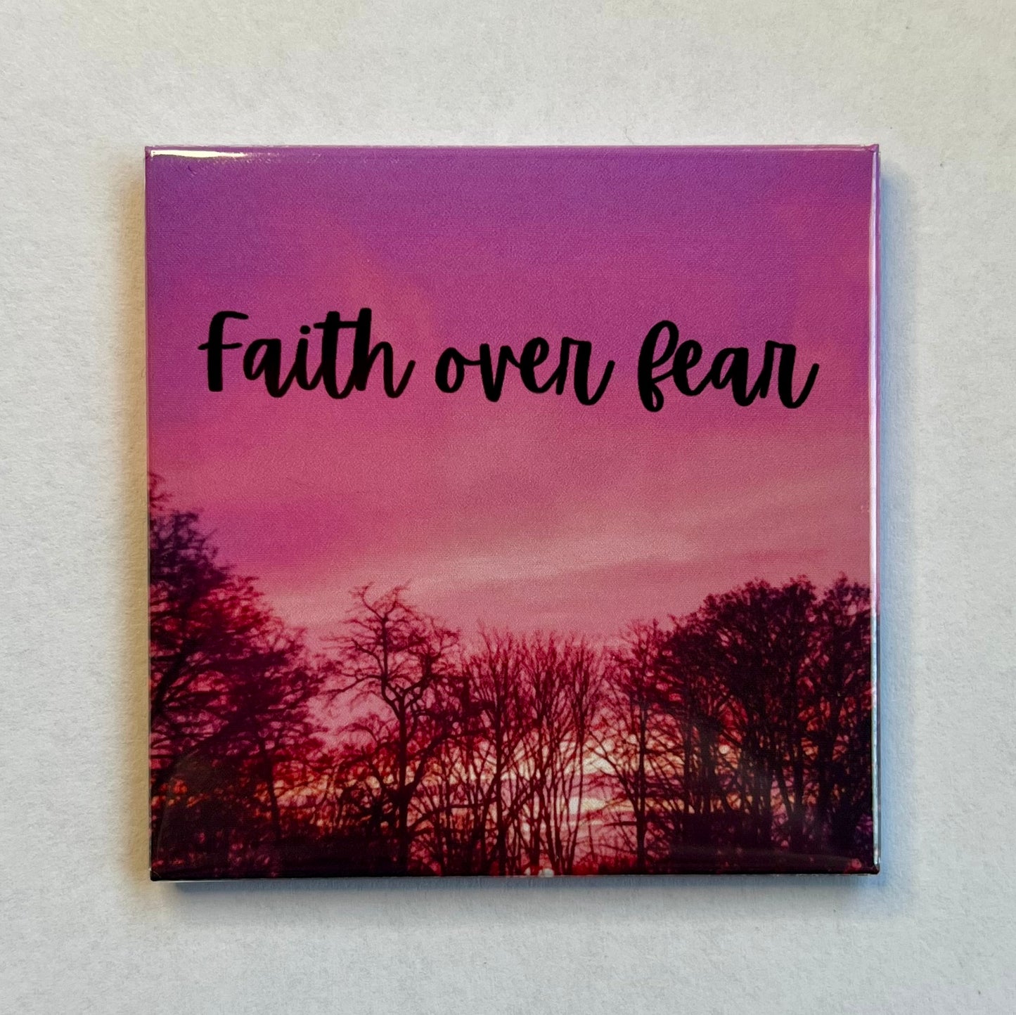 Christian magnet with deep pink sunset and trees reading Faith Over Fear