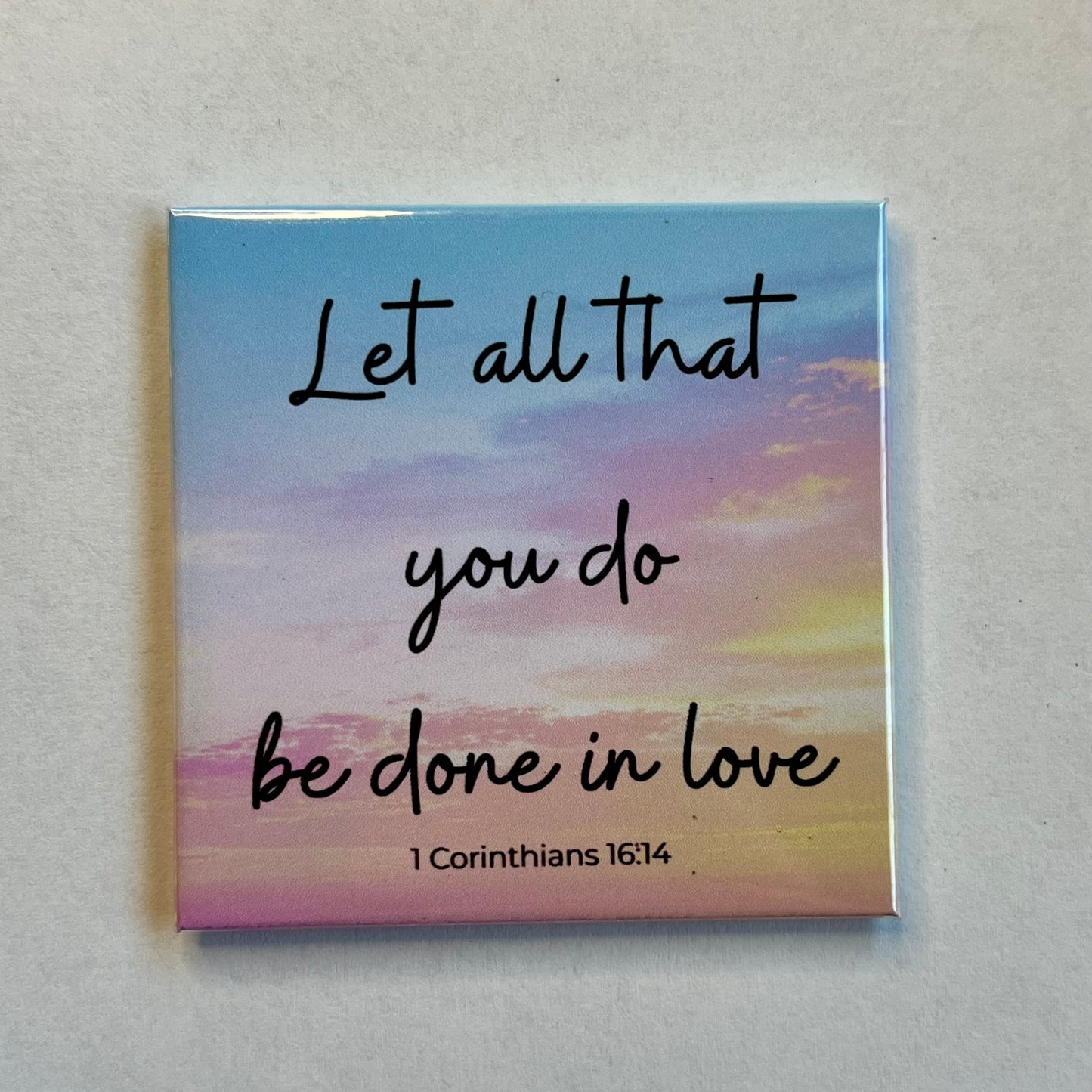 Christian scripture magnet with light sunset sky reading Let All That You Do Be Done in Love 1 Corinthians 16:14