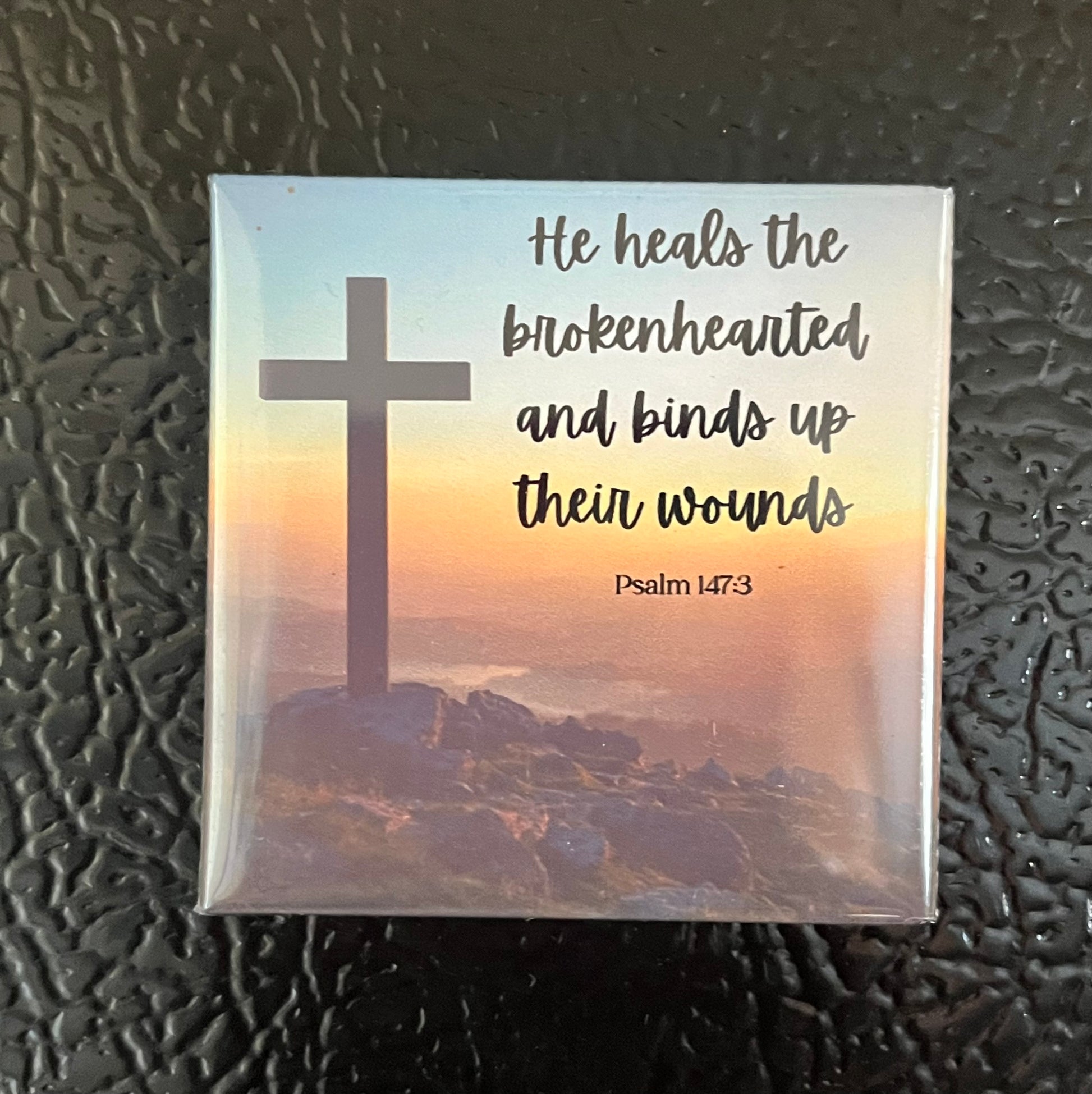 Psalms Scripture magnet on a fridge featuring a cross on a mountain at sunset with Psalm 147:3
