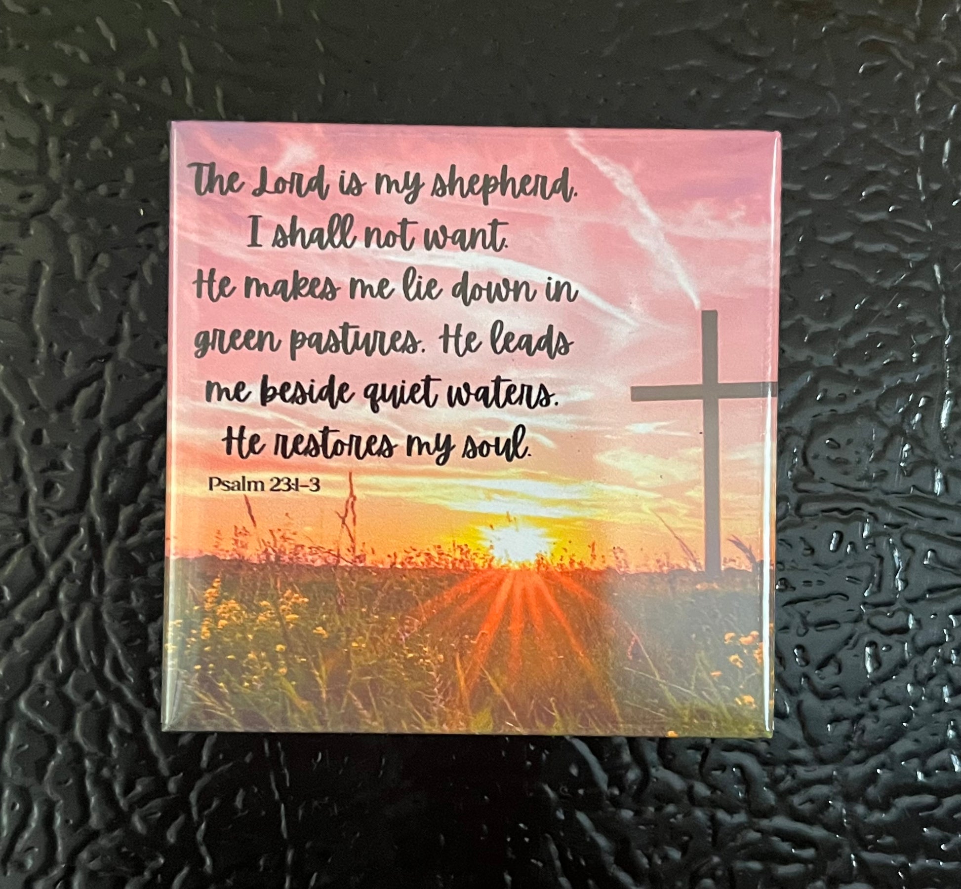 Psalms Scripture magnet on a fridge showing a cross in a field at sunrise with Psalm 23:1-3
